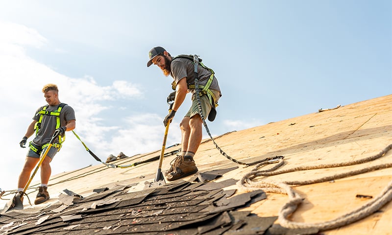 A roofing crew tearing off shingles ahead of a roofing installation